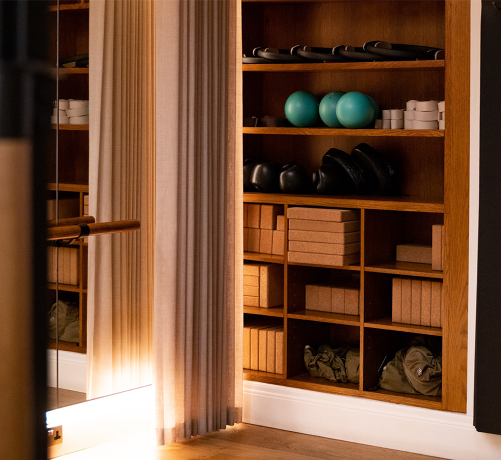 Shelves with yoga blocks, resistance bands, and props in Maslow’s softly lit wellbeing studio
