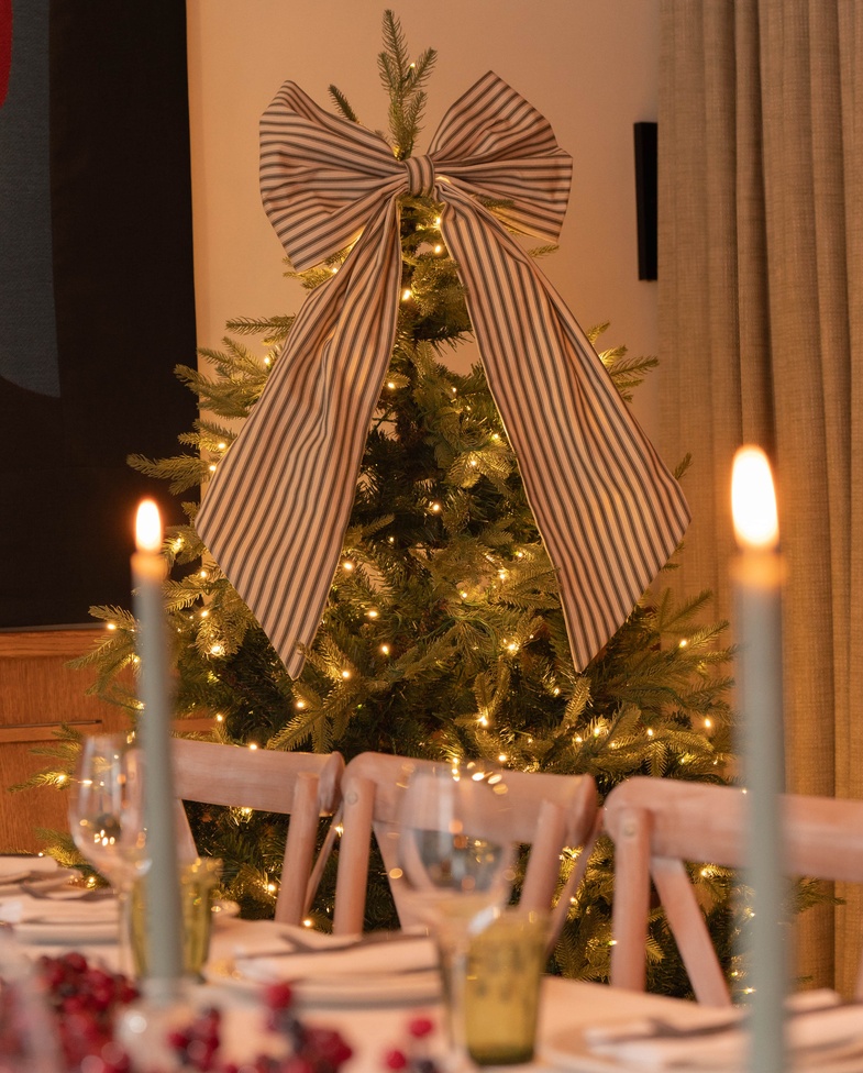 Festive Christmas tree with striped bow beside a candlelit private dining table at 1 Warwick in Soho, London.