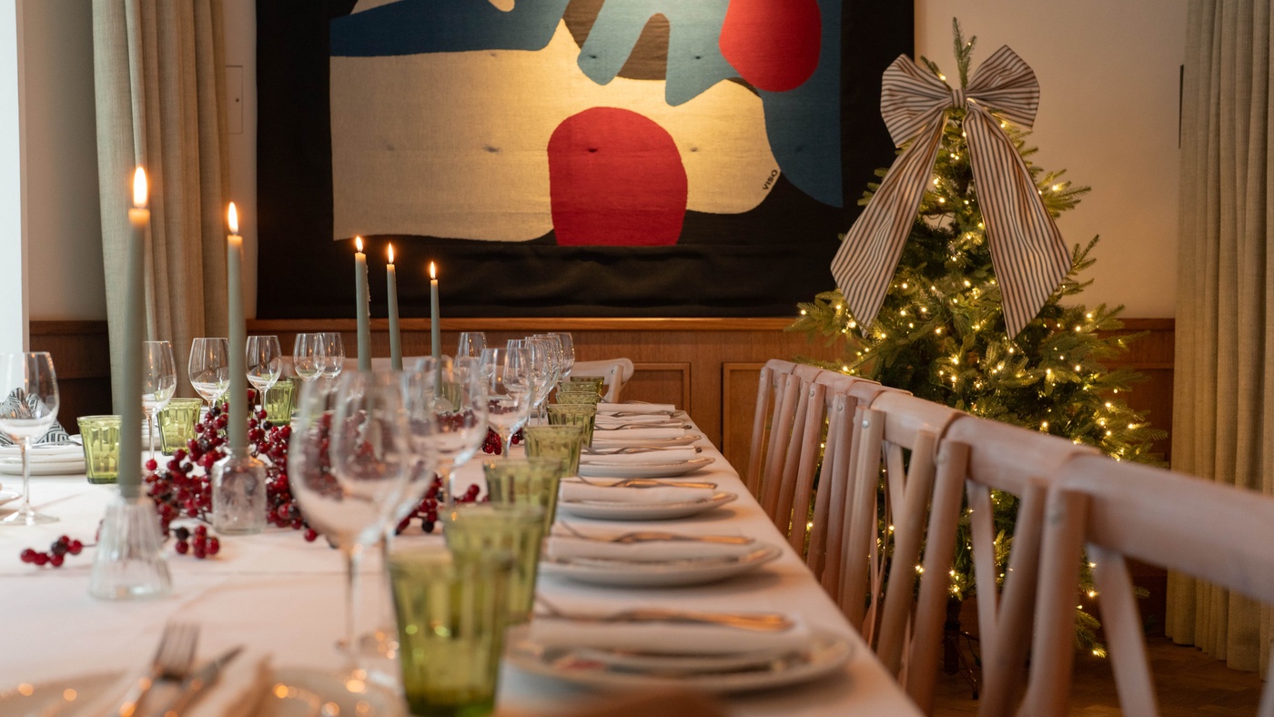 Candlelit Christmas private dining table at 1 Warwick in Soho, London, decorated with a Christmas tree, berries, and elegant place settings.