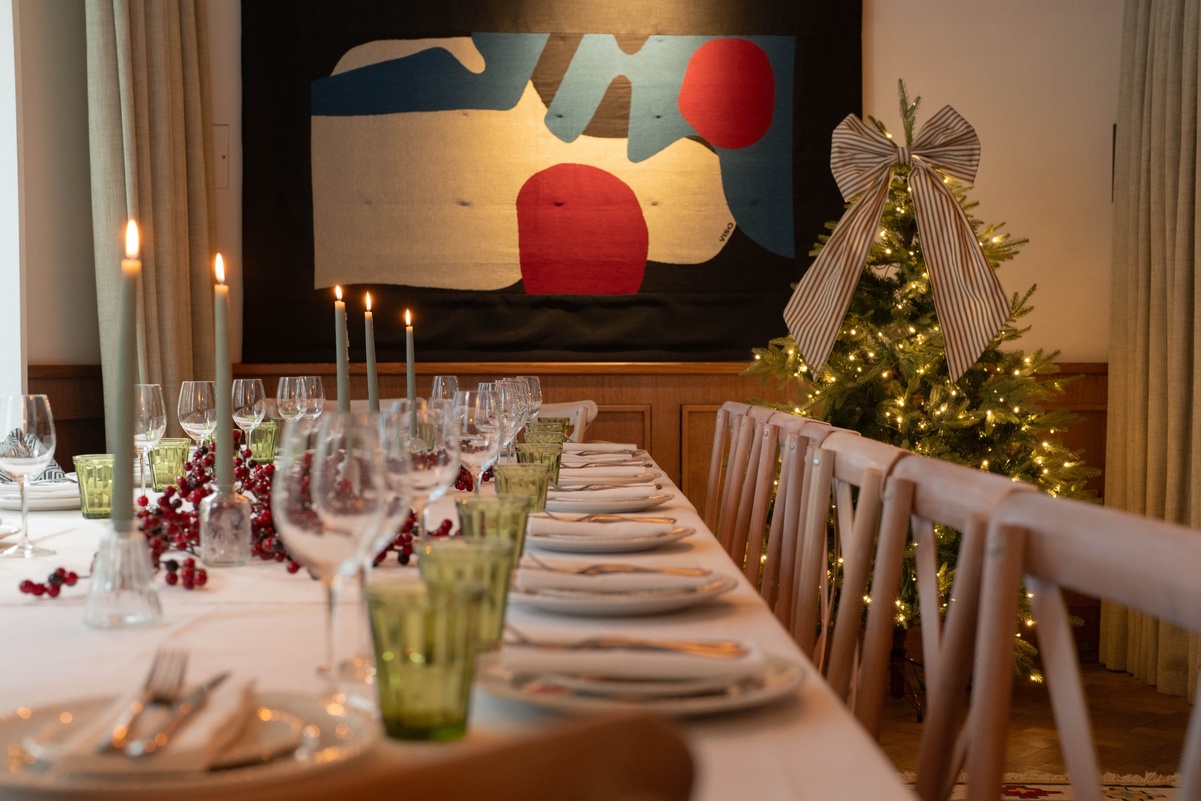 Candlelit Christmas private dining table at 1 Warwick in Soho, London, decorated with a Christmas tree, berries, and elegant place settings.