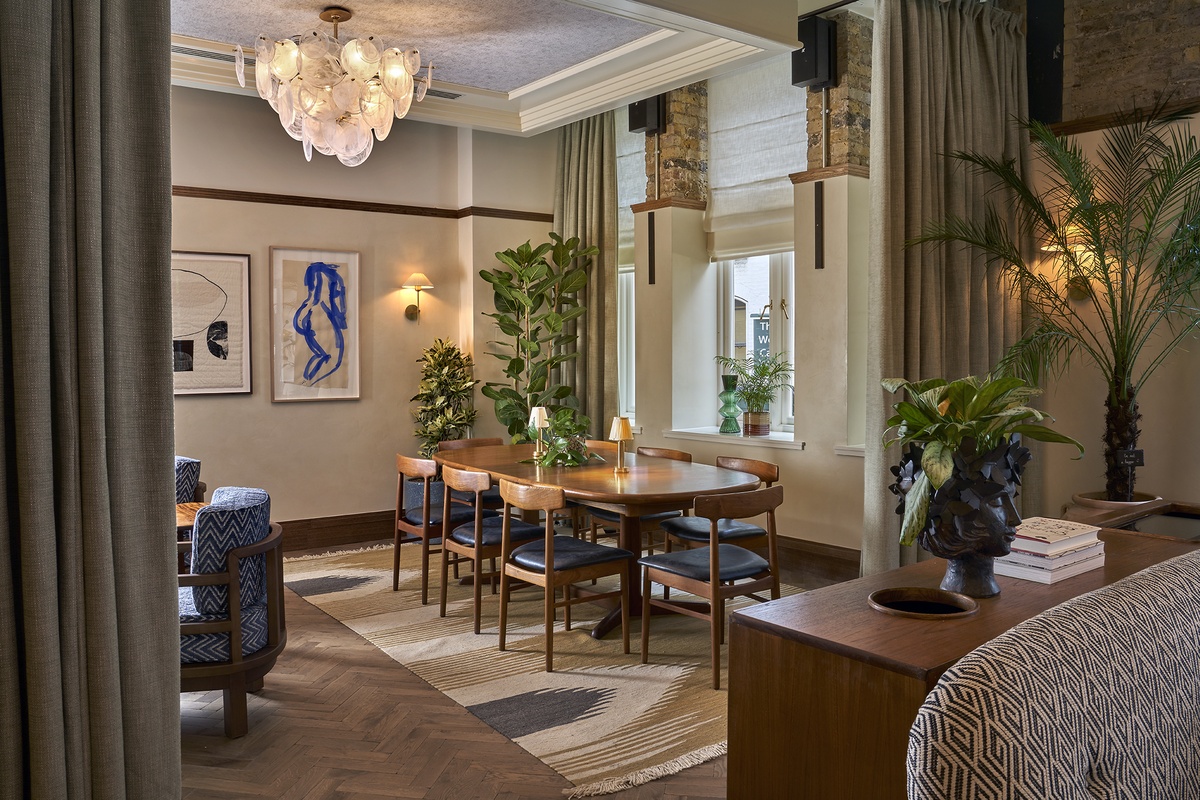 Stylish private dining room at 1 Warwick in Soho, London, featuring a mid-century table, plush seating, plants, and warm lighting.