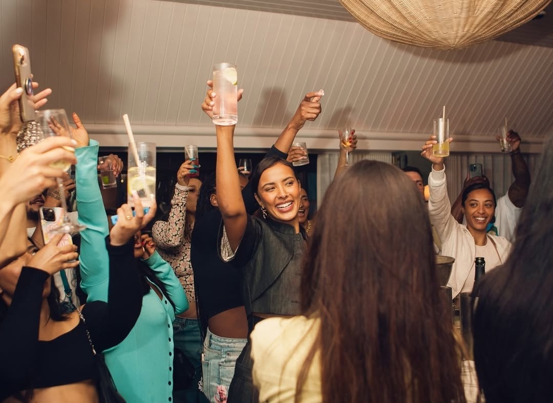 Group of people raising glasses in a festive toast during a lively rooftop celebration at Maslow’s in London.