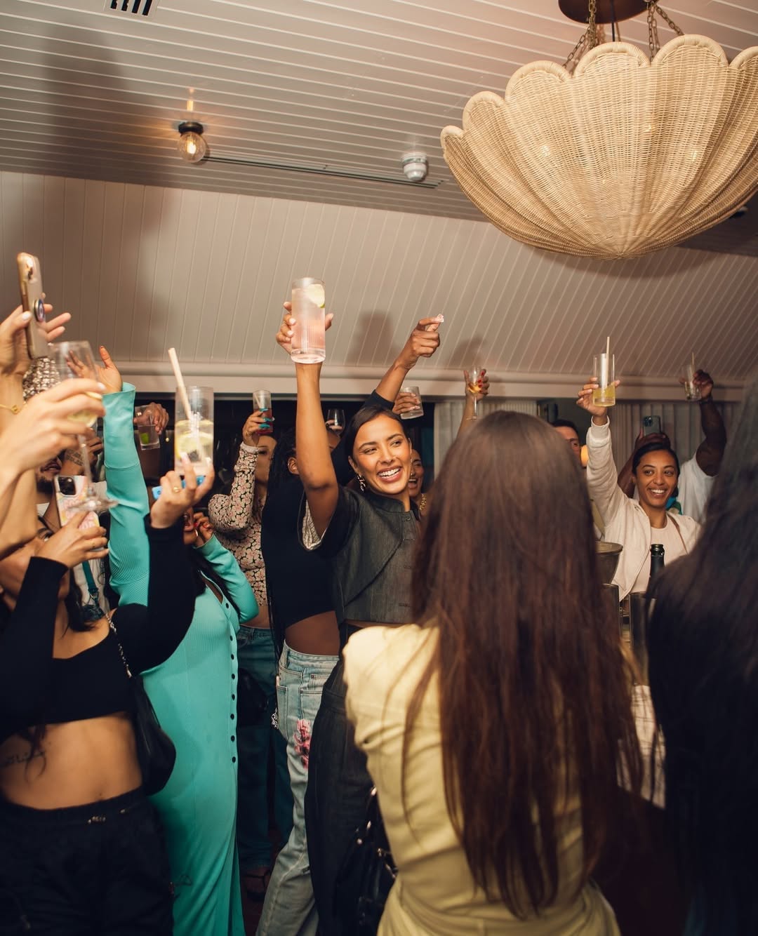 Group of people raising glasses in a festive toast during a lively rooftop celebration at Maslow’s in London.