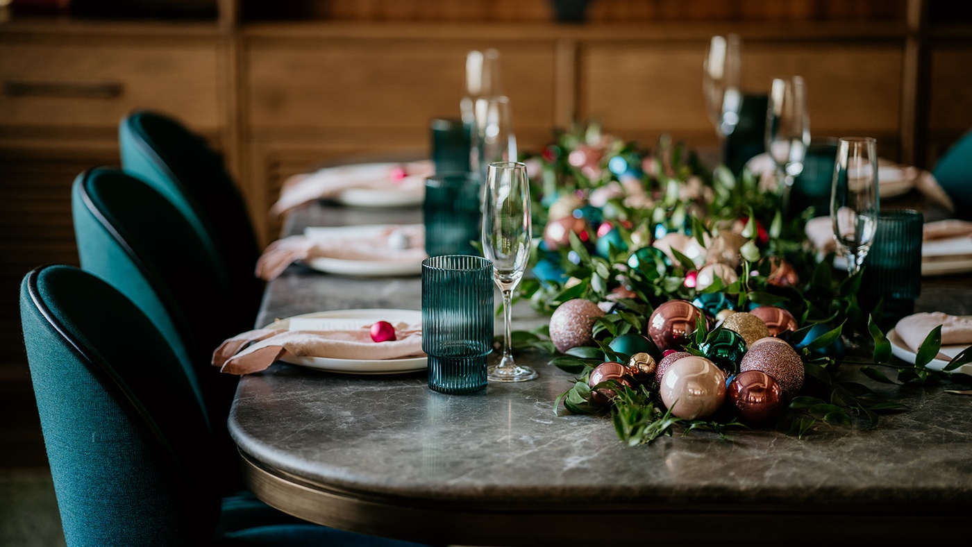 Close-up of a festive private dining table at Mortimer House in London, decorated with colourful Christmas baubles, greenery, and elegant place settings.