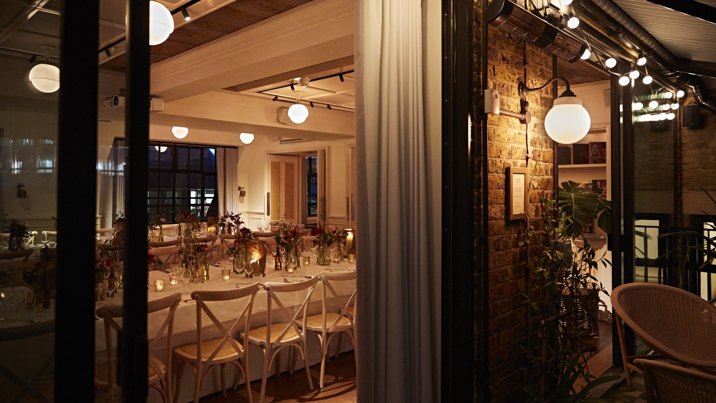 Warmly lit private dining room at Maslow’s Mortimer House in London, set with long tables, floral arrangements, and candlelight.