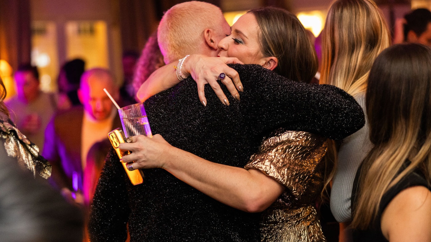 Two people embracing at a lively Christmas party at Maslow’s in London, surrounded by warm lighting and a festive crowd.