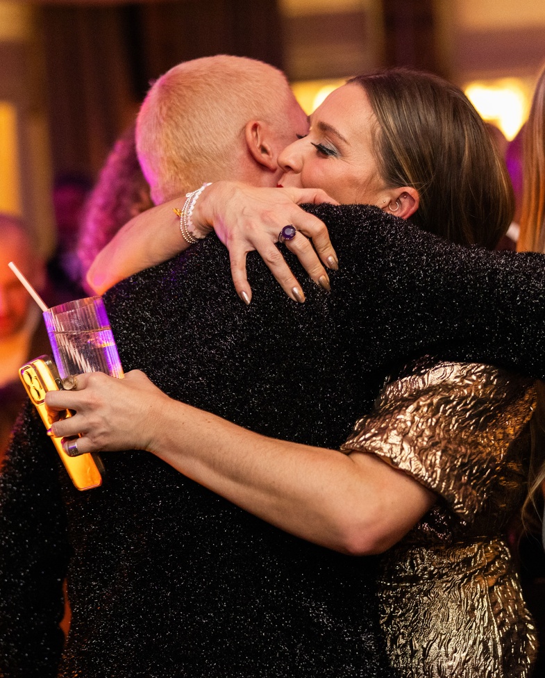 Two people embracing at a lively Christmas party at Maslow’s in London, surrounded by warm lighting and a festive crowd.