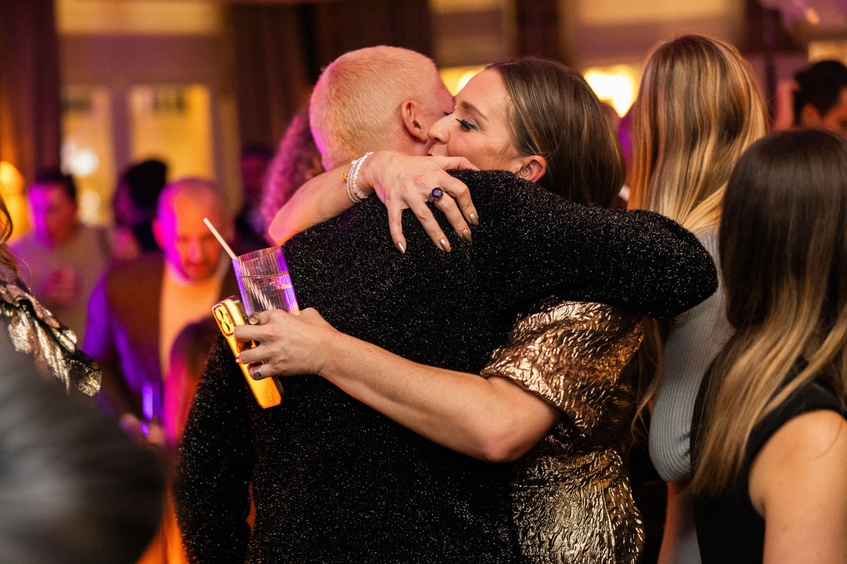 Two people embracing at a lively Christmas party at Maslow’s in London, surrounded by warm lighting and a festive crowd.