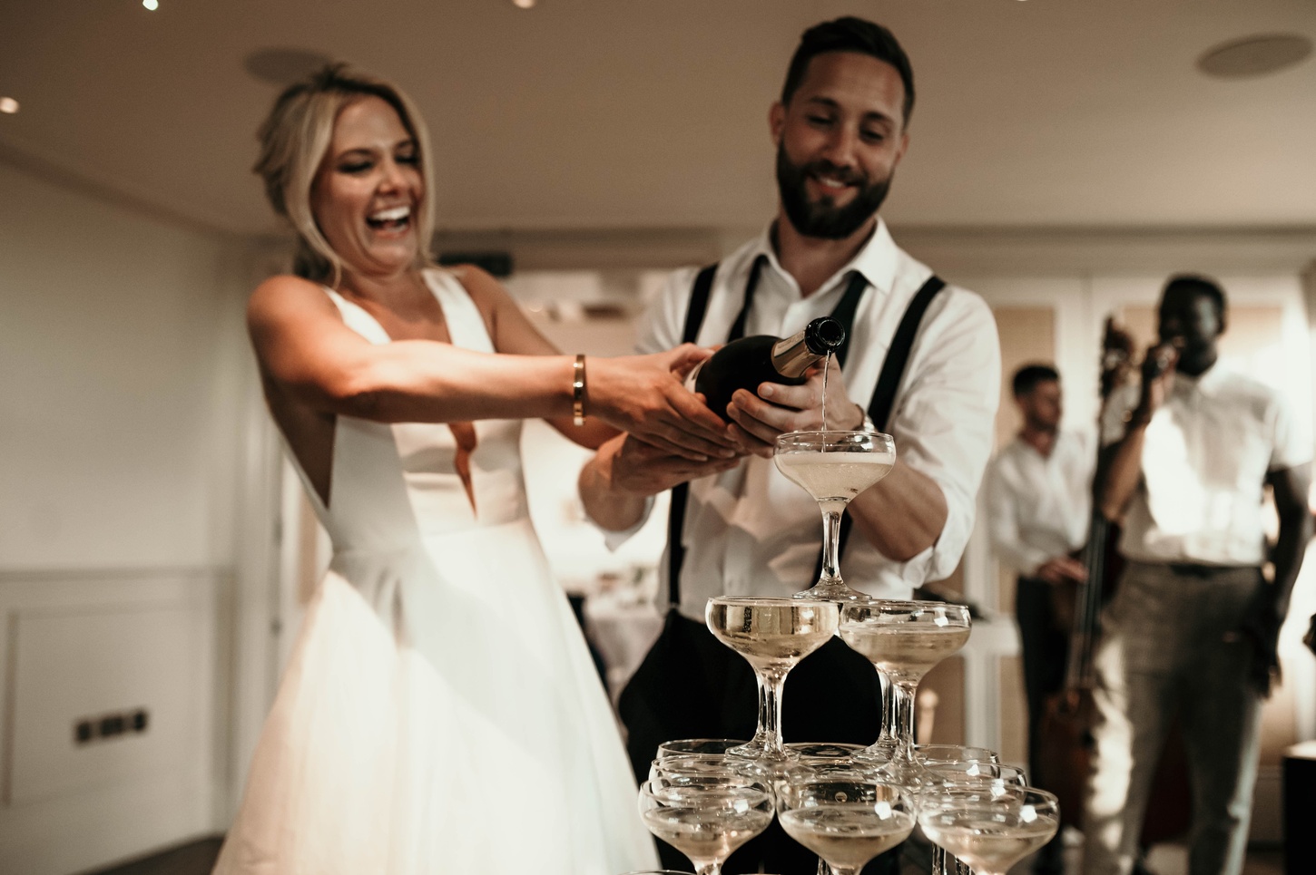 Photography by Alba Turnbull | Newlyweds pouring champagne into a champagne tower during an intimate wedding reception at a stylish Fitzrovia wedding at Mortimer House venue in central London.